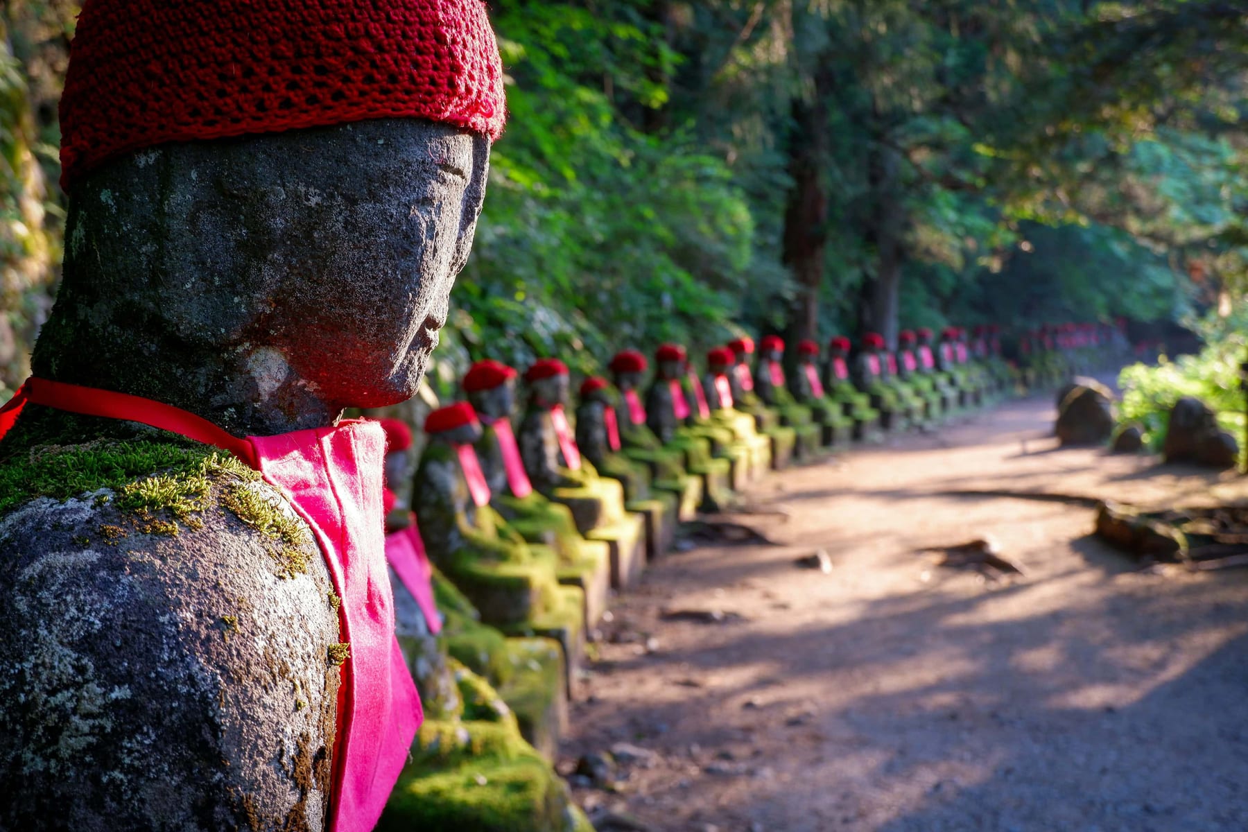 Row of Jizo statues wearing red bibs along the path at Kanmangafuchi Abyss, Nikko