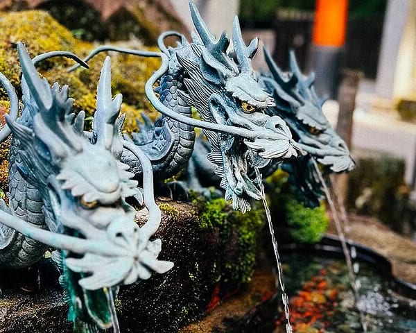 Bronze dragon head water spouts at a purification fountain outside a Shinto shrine in Japan