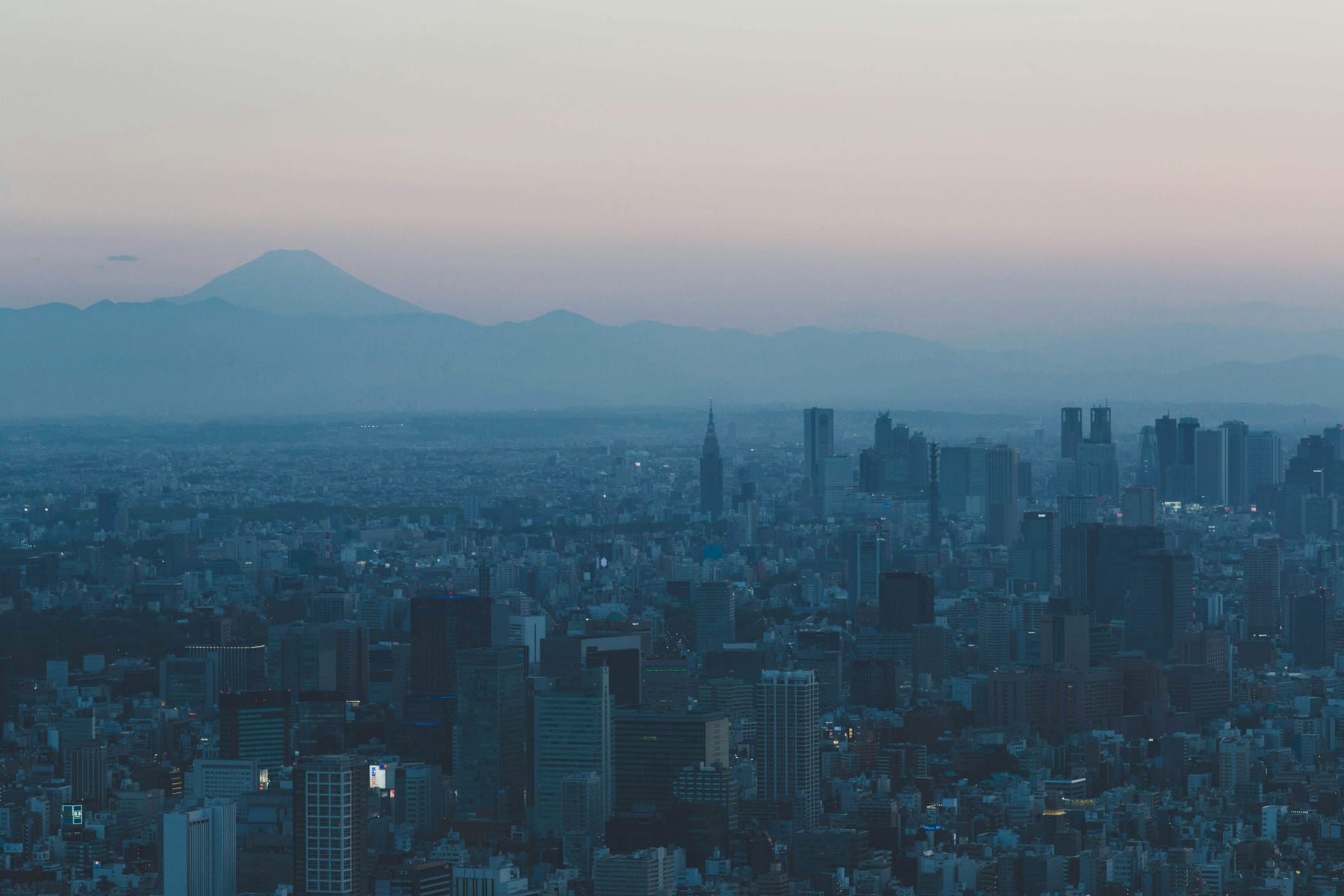 Mount Fuji seen at dusk from the Tokyo Skytree observation deck, with the city skyline and towers in the foreground