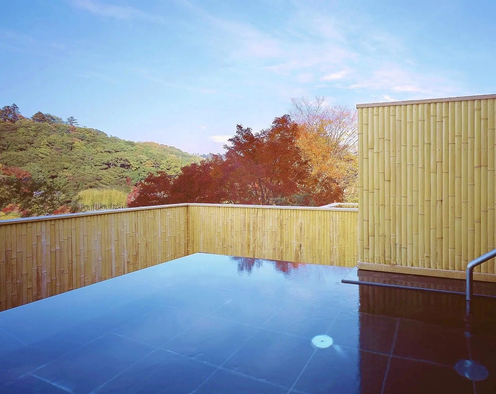An open-air hot spring bath at Sora Togetsusou Kinryu, with autumn colour beyond