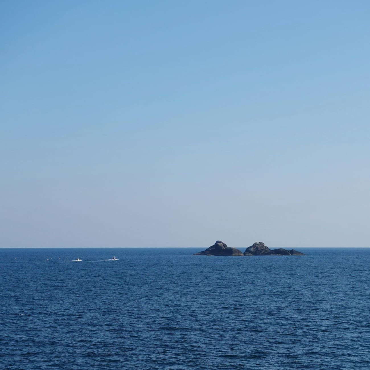 Calm blue sea with two small rocky islets off the coast of Kumamoto