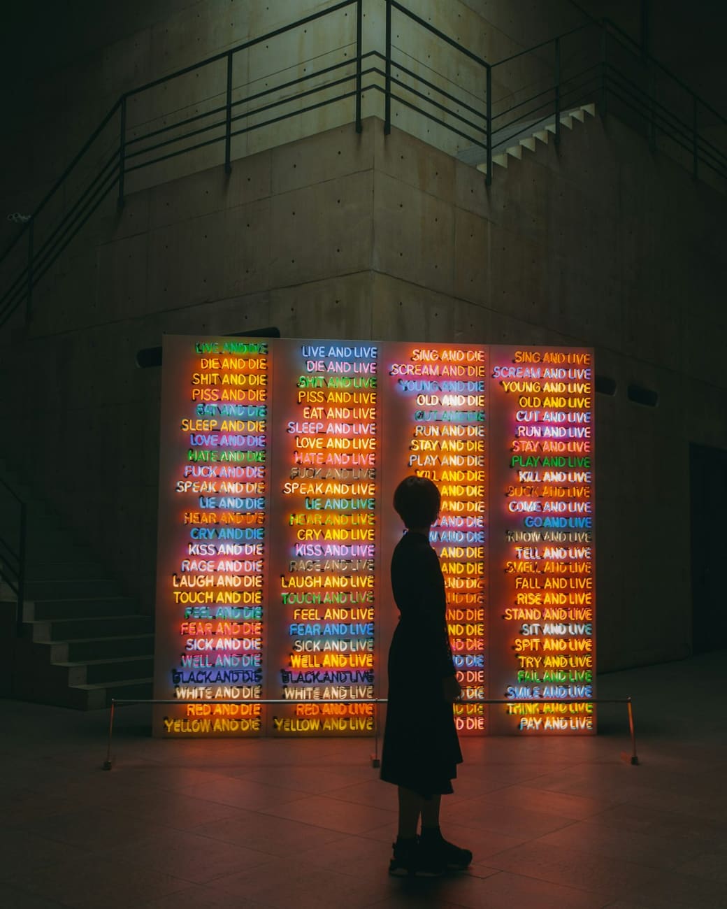 A visitor before an installation of coloured light in a dark room